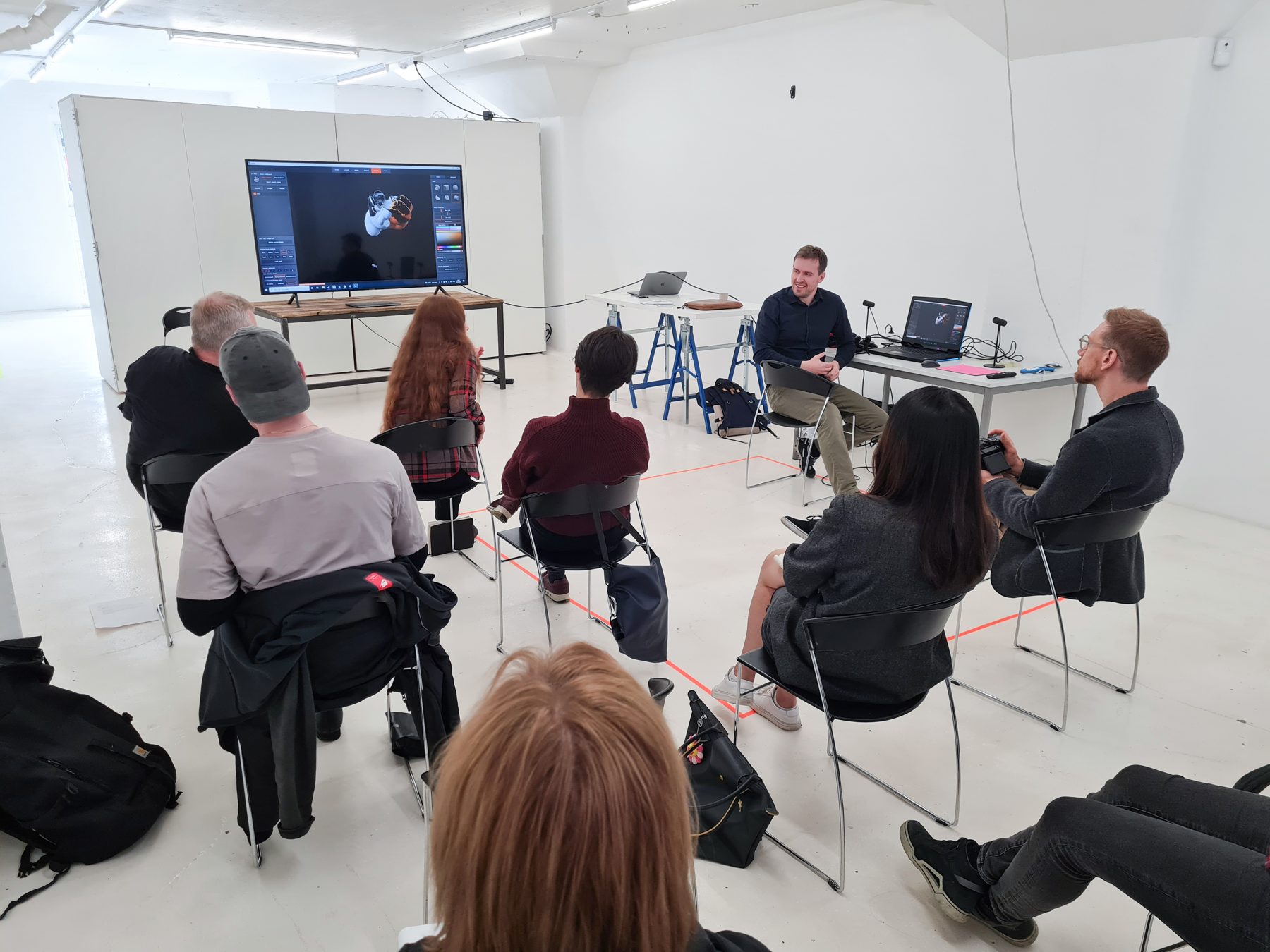 A course group seated around a screen in the project room