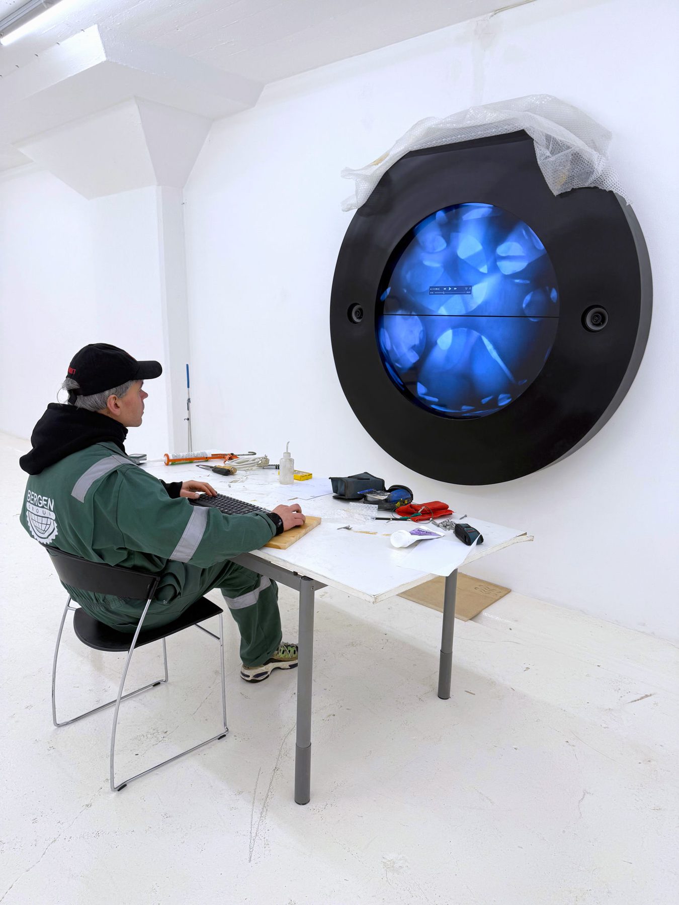 A video sculpture being installed on the gallery wall