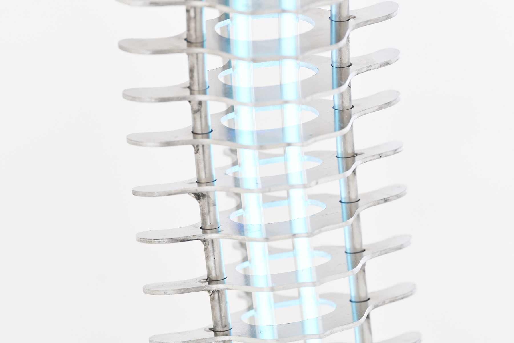 Detail of a stacked aluminium sculpture lit blue from inside