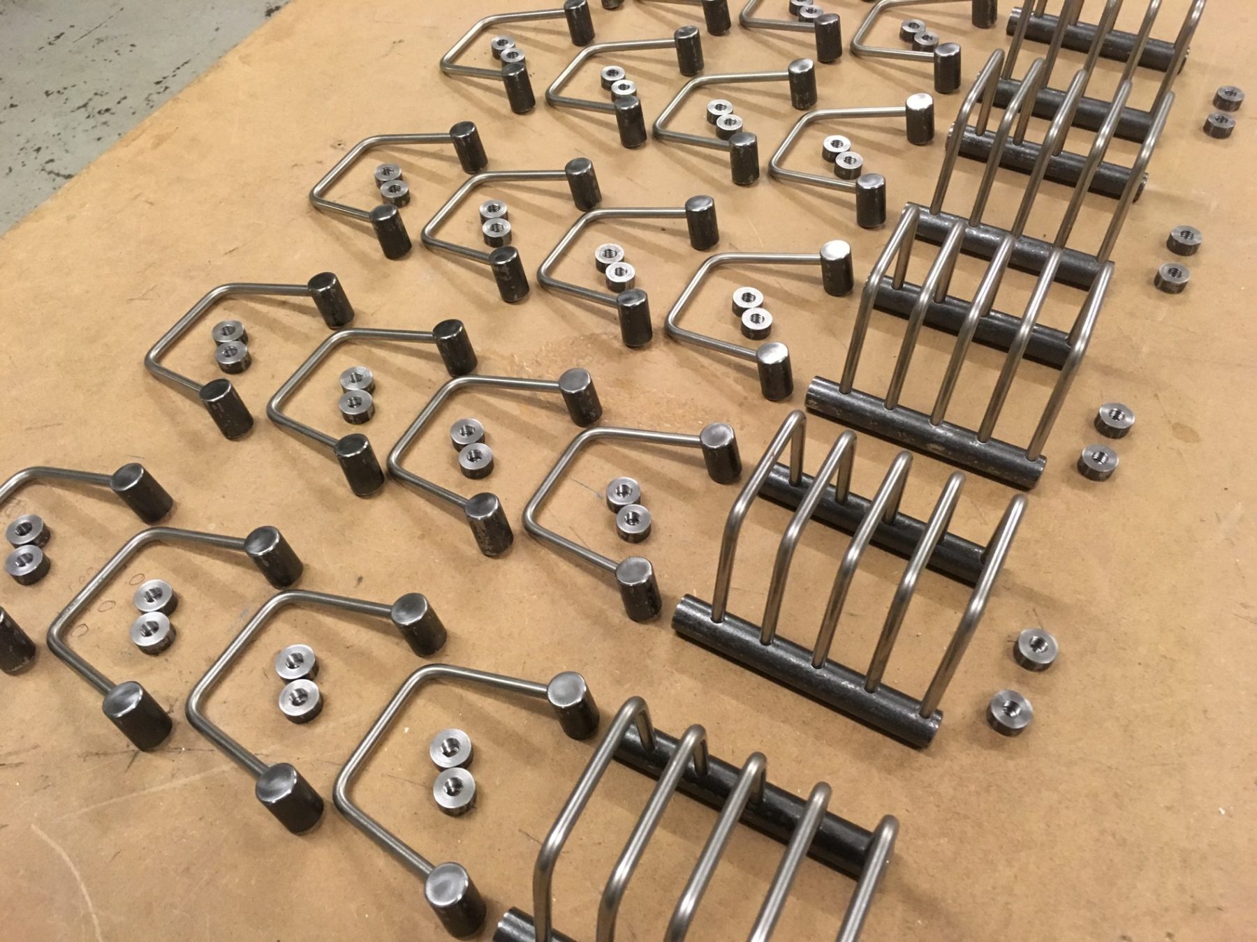Rows of bent stainless-steel brackets laid out on a workbench