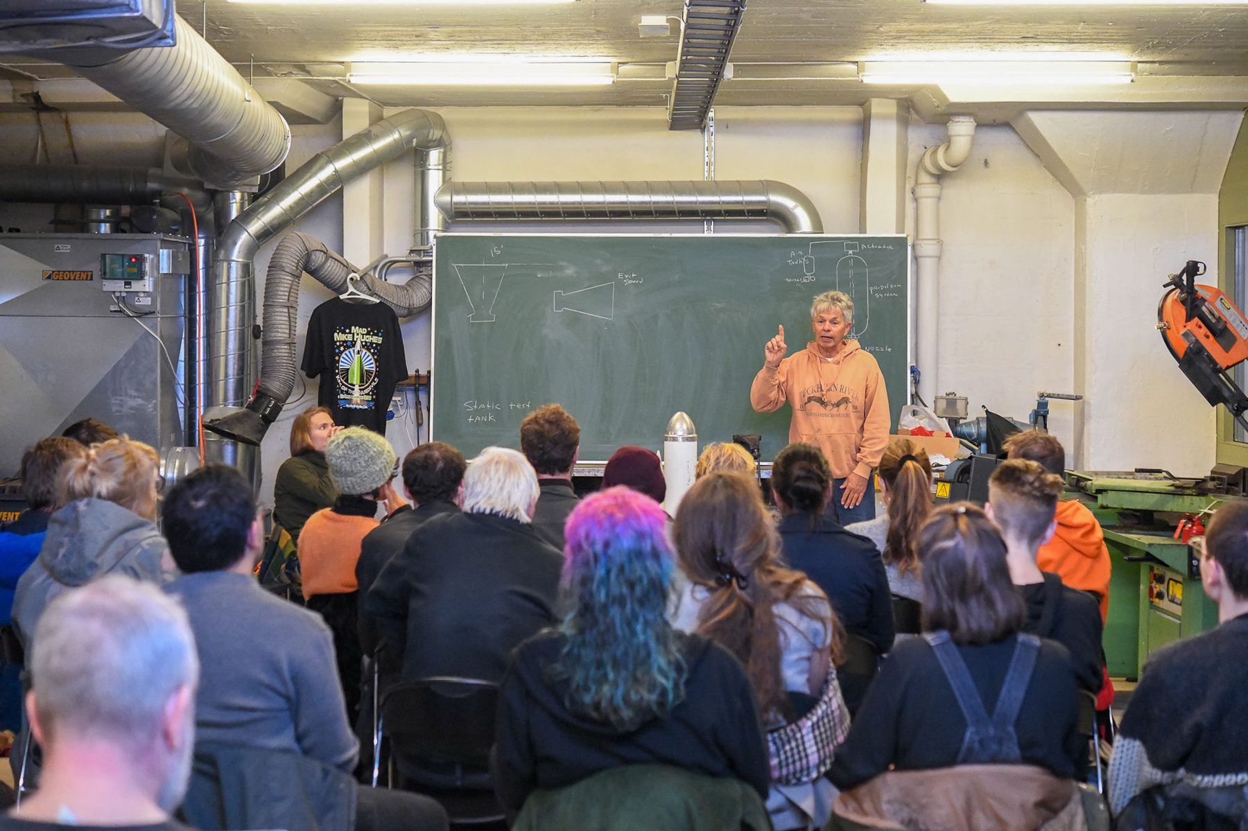 A talk in the metal workshop with a full audience